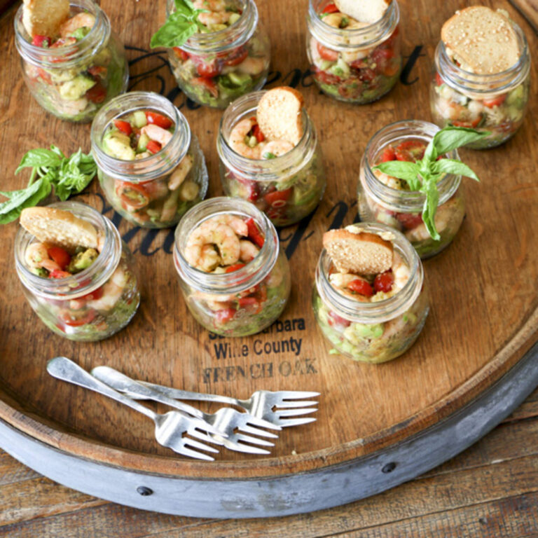Shrimp and avocado salad mason jars arranged in a circle with basil garnish on a French oak wine barrel