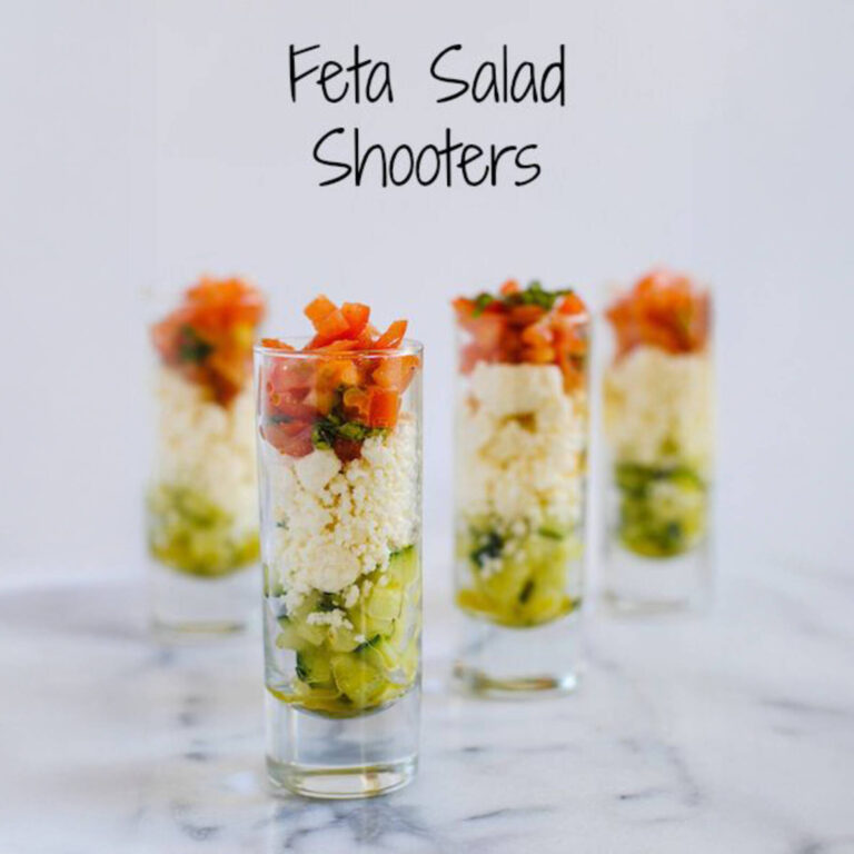 Feta salad shooters with cucumber, tomato, and feta cheese layered in tall shot glasses