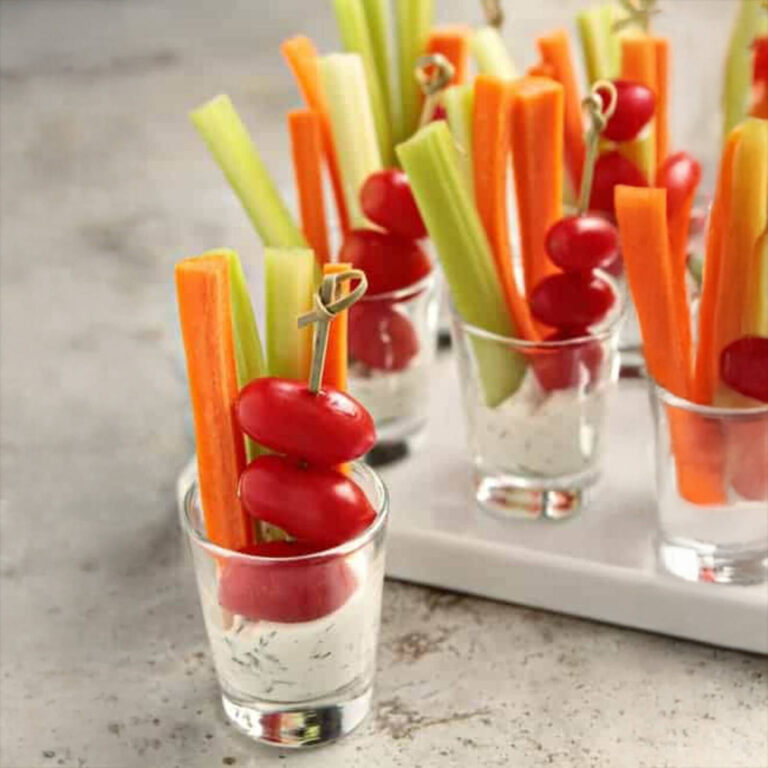 Vegetable stick shooters with celery, carrot, and cherry tomato in ranch dip