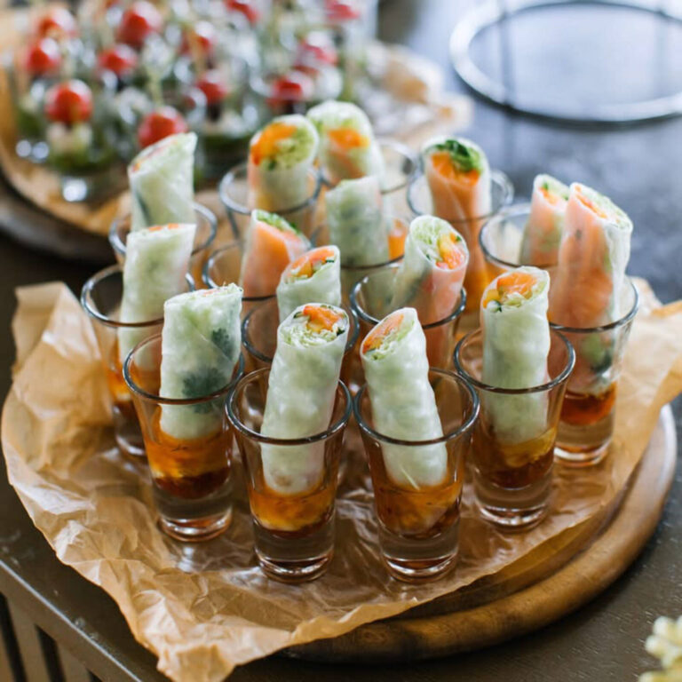 Fresh rice paper spring rolls with shrimp and veggies served upright in shot glasses with dipping sauce