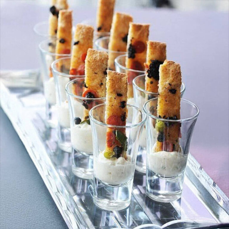 Baked breadstick appetizers in shot glasses of whipped feta dip with olives and cherry tomatoes
