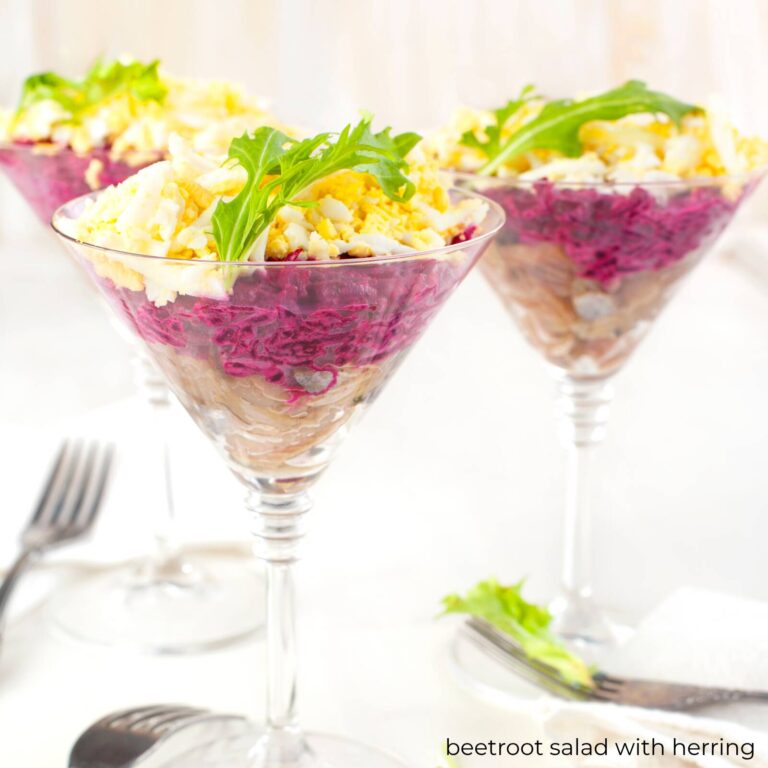 Beetroot salad with herring in stemmed glasses, layered with chopped egg and arugula