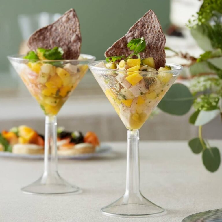 Ceviche with diced mango and pineapple in martini glasses, each with a tortilla chip garnish