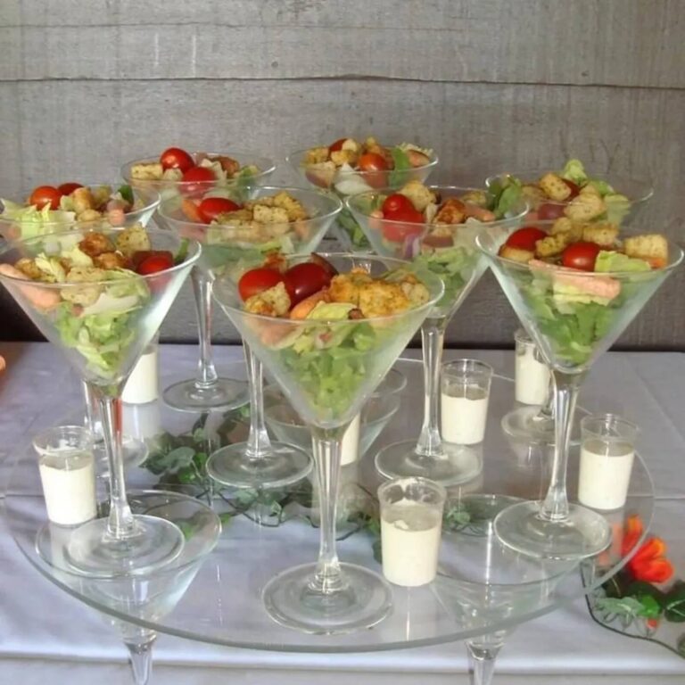 Caesar salad in martini glasses on a glass platter with small cups of dressing tucked between the stems
