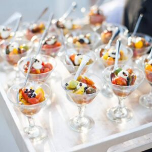 Tomato and burrata appetizer bites in coupe glasses with balsamic caviar pearls, served with spoons