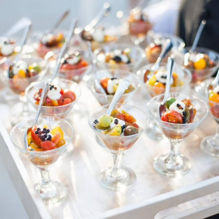 Tomato and burrata appetizer bites in coupe glasses with balsamic caviar pearls, served with spoons