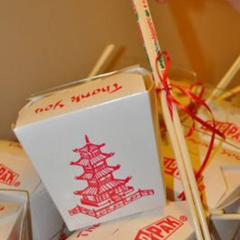White pagoda-print takeout box with a handwritten “Thank You” note and red ribbon-tied chopsticks