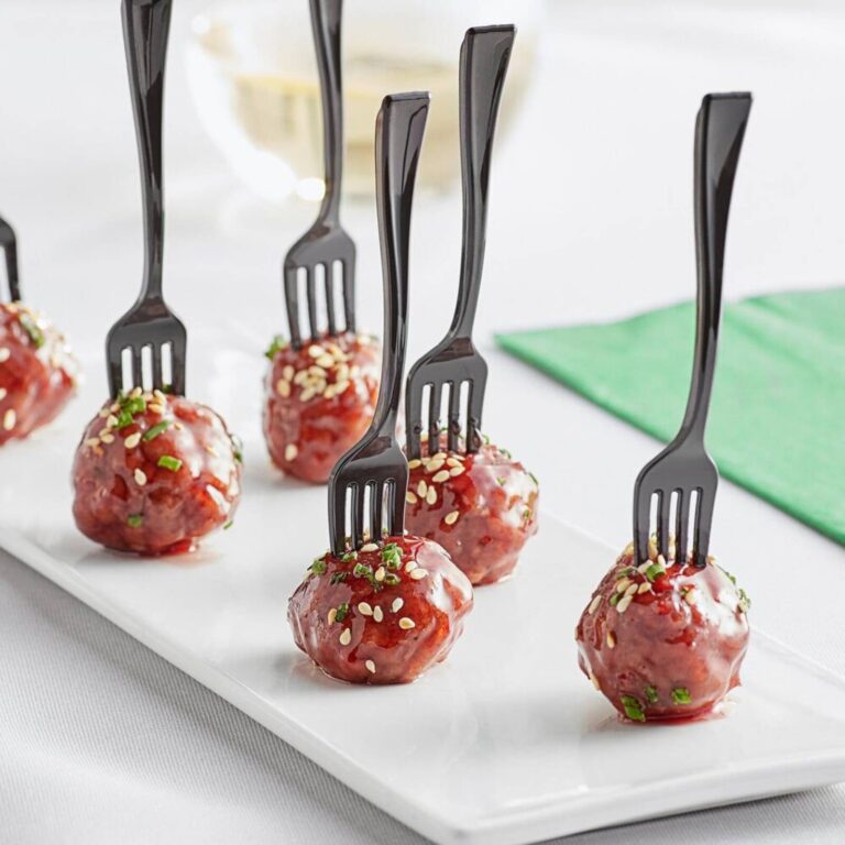 Glazed cocktail meatballs with sesame seeds and chives on black forks