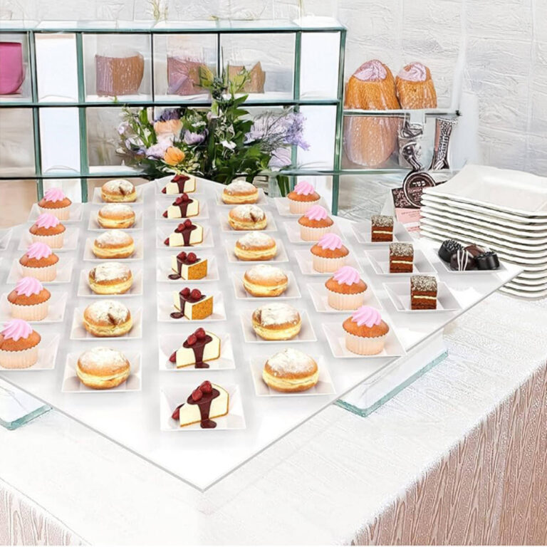 Assorted mini desserts including cupcakes, donuts, and cheesecake slices on square tasting plates at a dessert display