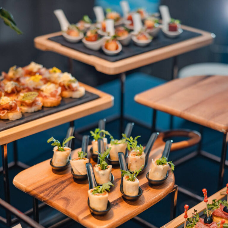 Tiered catering display of tasting spoon appetizers including salmon verrine and bruschetta