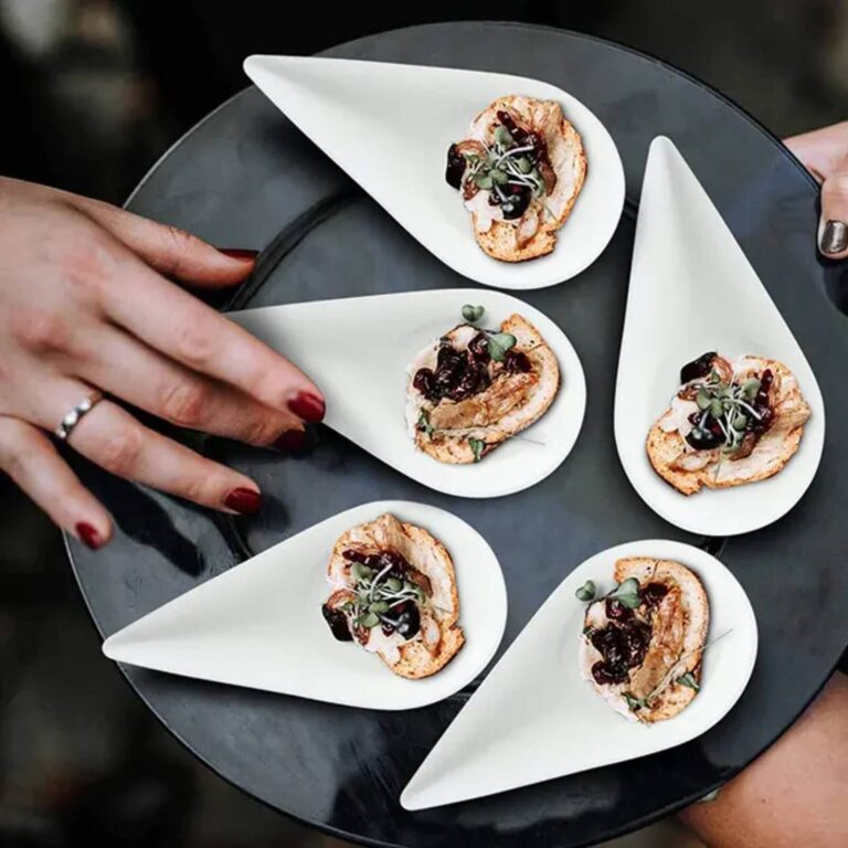 Chicken bites with cranberry sauce served on white teardrop tasting spoons