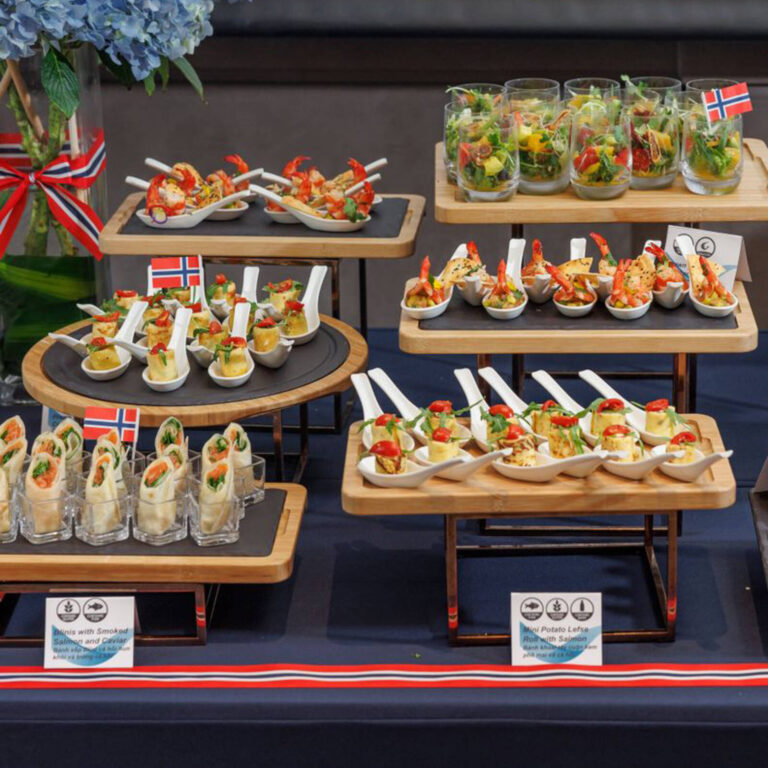 Tiered Norwegian-themed catering display with shrimp, salmon wraps, and potato lefse tasting spoon bites
