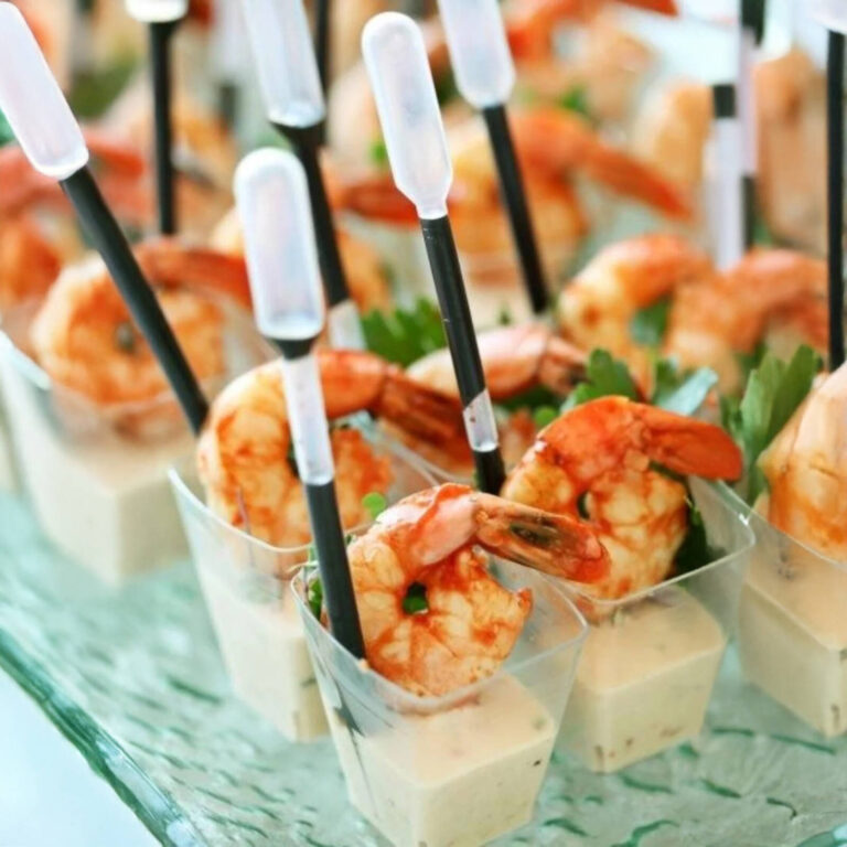 Shrimp cocktail cups with sauce pipettes on a glass tray garnished with parsley