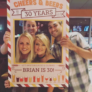 group of friends holding up a Cheers & Beers to 30 Years photo booth prop frame
