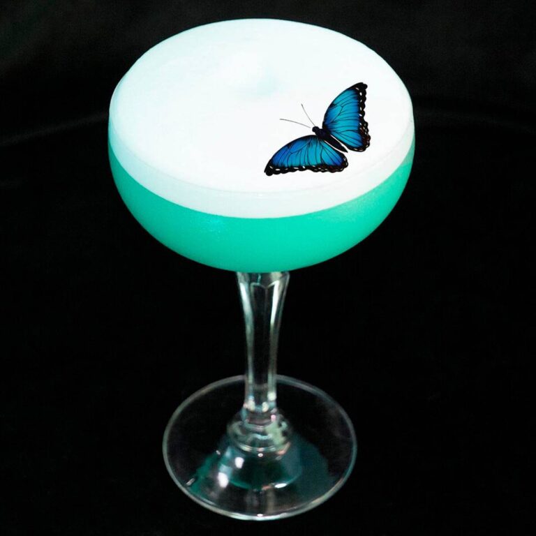 Edible blue butterfly topper on a teal foam-topped cocktail