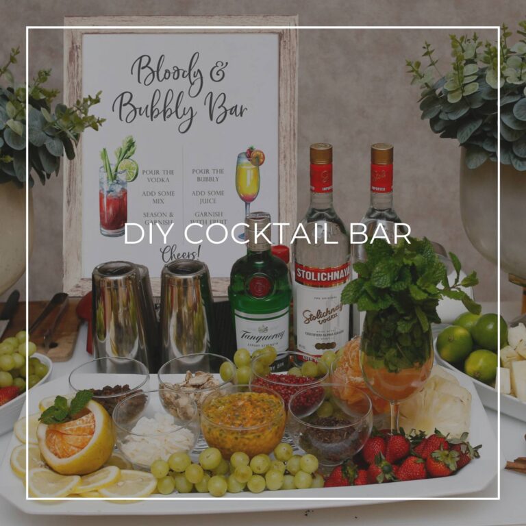 DIY cocktail bar with liquor, ingredients, and a cocktail recipe sign for party guests to make their own drink