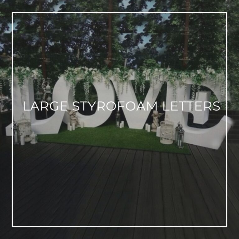 large white styrofoam letters spelling LOVE dressed with greenery and flowers at an event