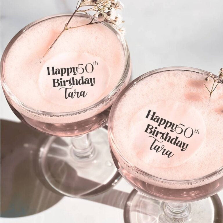 Edible script topper reading "Happy 50th Birthday Tara" on a cocktail with baby's breath