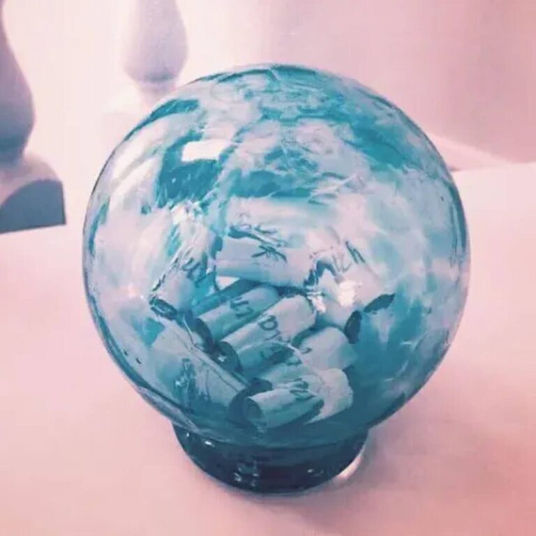 Close-up of a teal blue glass wishing ball filled with rolled paper wishes