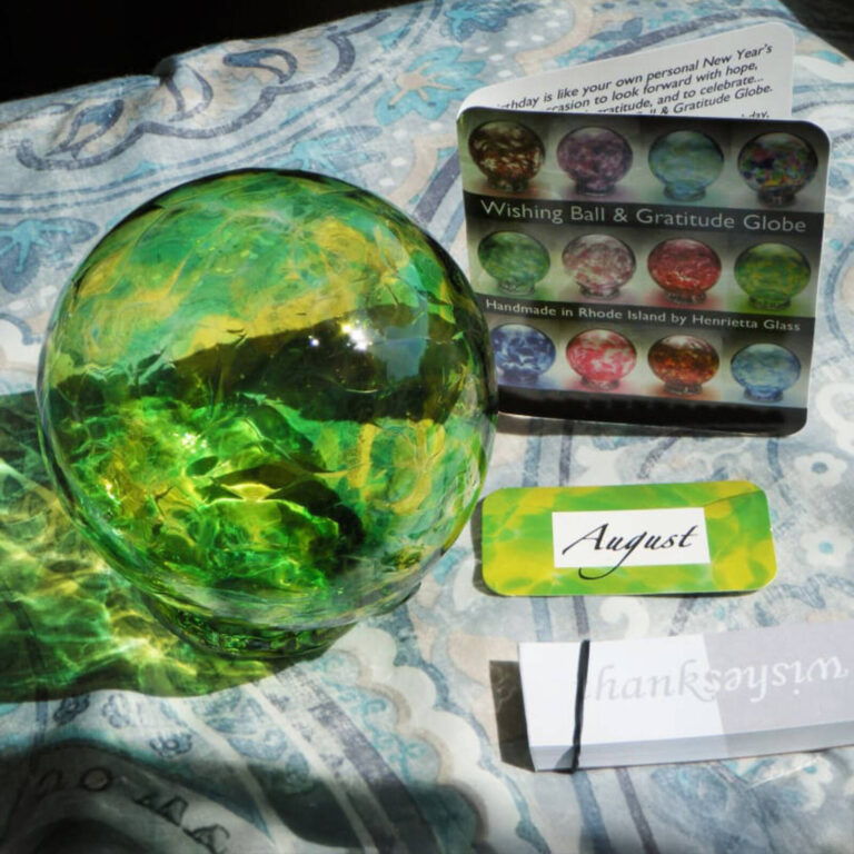 Green glass wishing ball with an August date card and Wishing Ball and Gratitude Globe catalog card