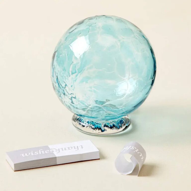 Light blue glass wishing ball on a plain background with wishes and thanks tags